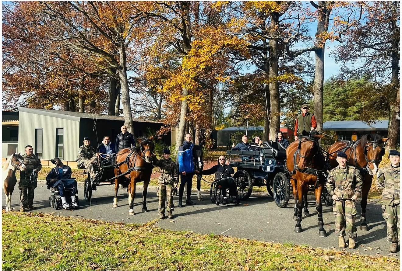 Sortie en attelage adapté : des pensionnaires de l'INI en fauteuil roulant participent à une activité de meneur d'attelage, avec chevaux et calèches, encadrés par des militaires, dans un parc en automne