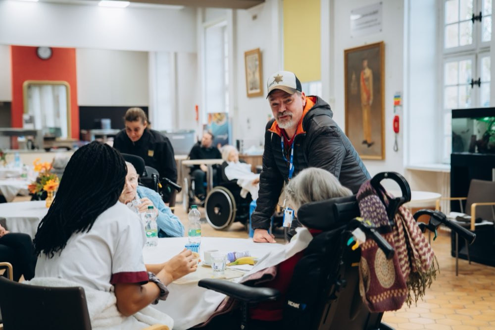 Un visiteur échange chaleureusement avec des pensionnaires dans la salle commune de l'INI