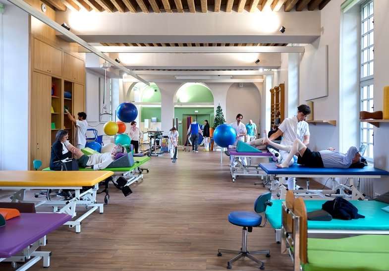 Vue d'ensemble de la salle de rééducation de l'INI : patients et kinésithérapeutes en séance sur les tables de rééducation