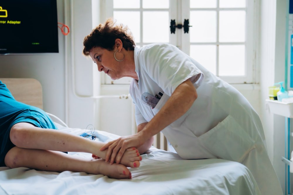 Une soignante de l'INI prodigue un soin à la jambe d'un patient alité