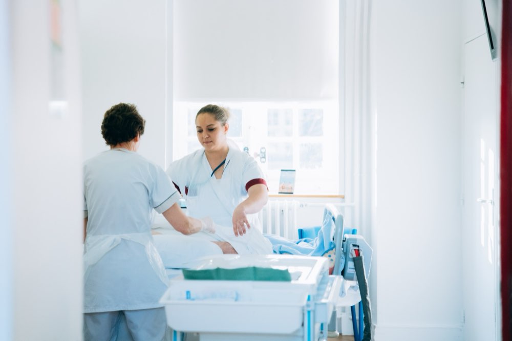 Deux soignantes prodiguent des soins à un patient alité