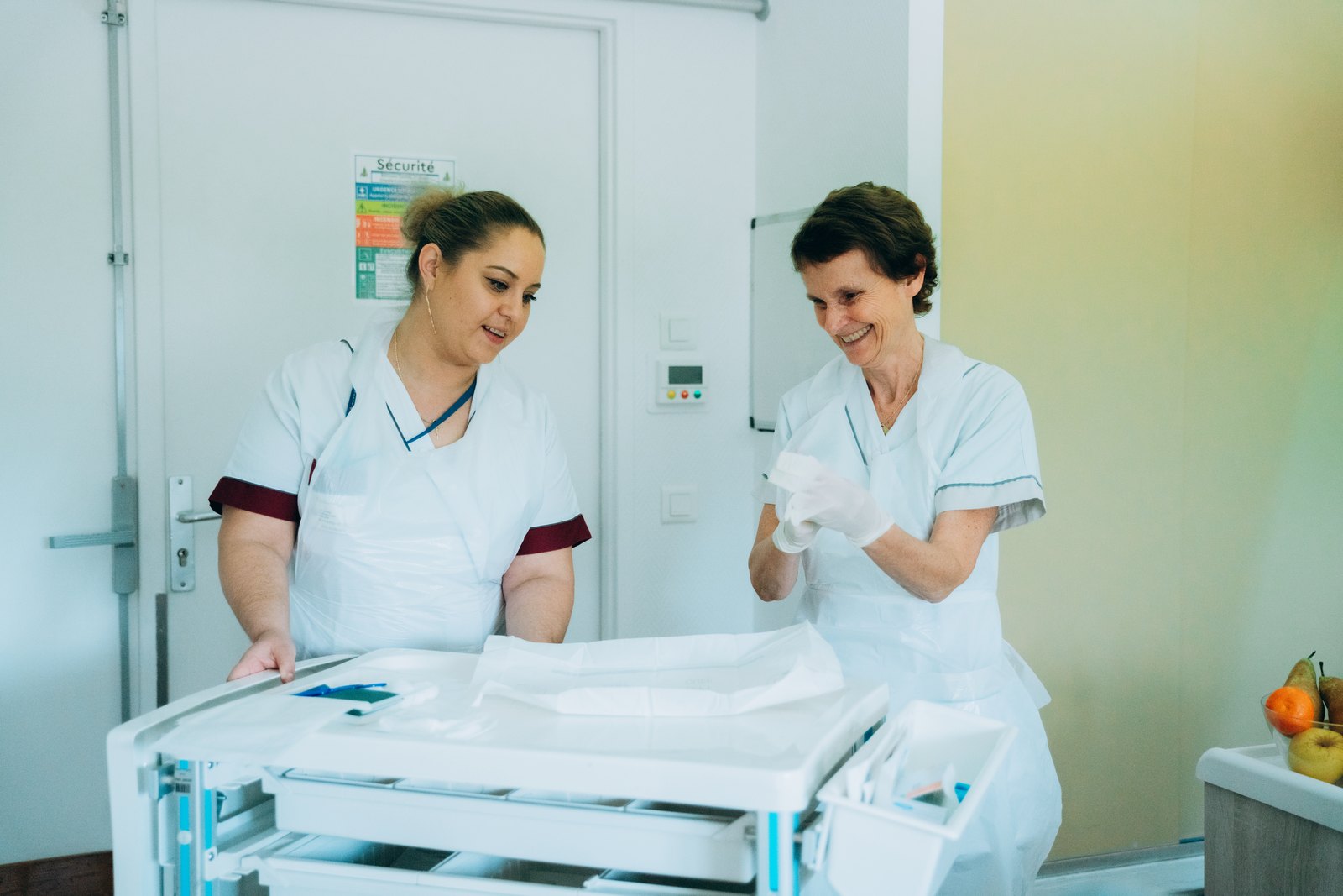 Deux infirmières de l'INI, souriantes, préparent un chariot de soins stérile dans une salle de l'Institution